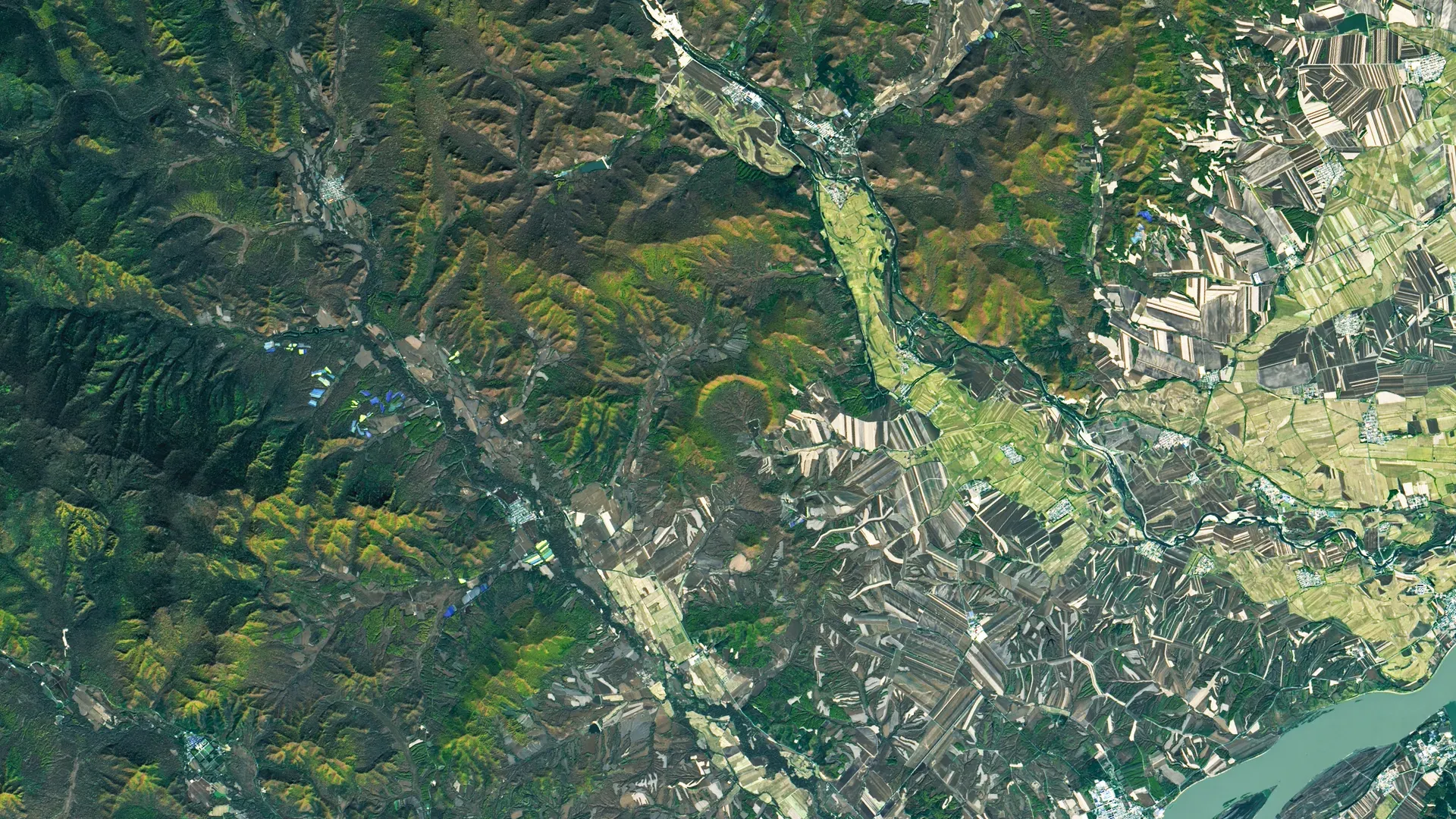 Satellite view of green hills, fields and a river around Yilan town