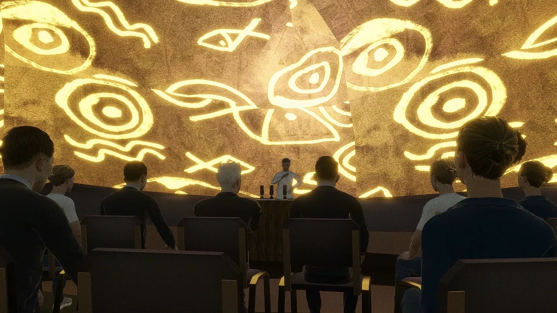 Audience seen from behind facing a speaker at a podium under golden patterned walls